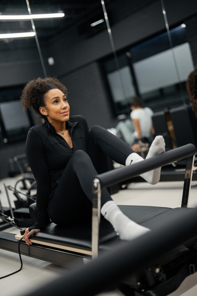 Actiefoto van een Reformer Pilates les met begeleiding in kleine groep.
